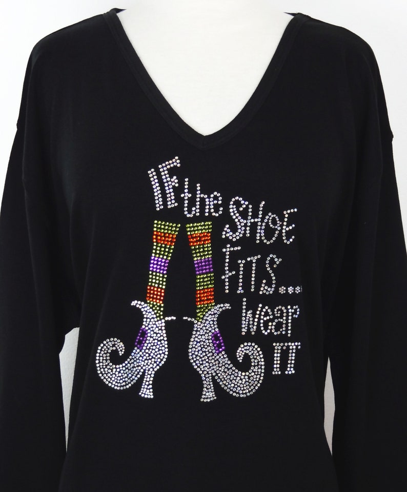 May include: Black long-sleeved shirt with a sparkly design of witch's shoes and the text "If the shoe fits... wear it".