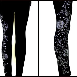 May include: Black leggings with a silver rhinestone floral design. The design features roses, leaves, and swirls.