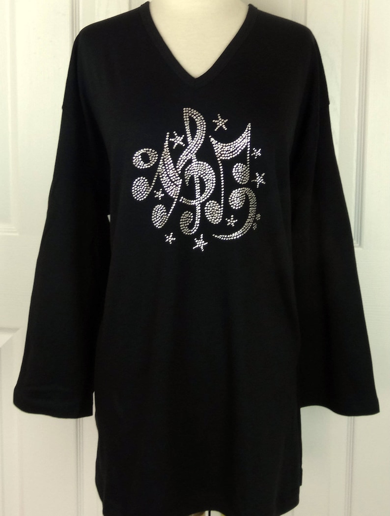May include: Black long-sleeved v-neck t-shirt with a rhinestone design of musical notes and stars.