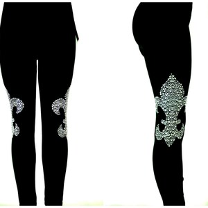 May include: Black leggings with a sparkling, white fleur-de-lis design on the knees. The leggings are made of a stretchy material and are suitable for various activities. The fleur-de-lis is a classic symbol, adding a touch of elegance to the leggings.