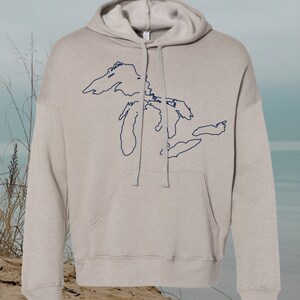 May include: A light gray hooded sweatshirt with a navy blue outline of the Great Lakes on the front.