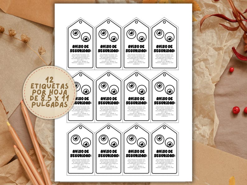 May include: A sheet of white paper with twelve black and white security tags. Each tag has a cartoon eye design and the text "AVISO DE SEGURIDAD". A circular label reads "12 ETIQUETAS POR HOJA DE 8.5 X 11 PULGADAS".