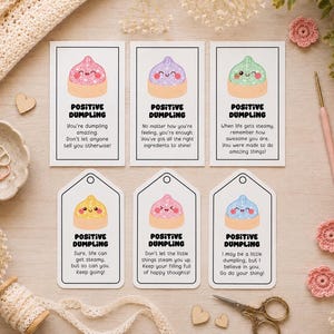 Puede incluir: Seis tarjetas rectangulares y con forma de etiqueta que muestran ilustraciones de dumplings sonrientes con partes superiores brillantes en rosa, morado, verde, amarillo y azul. Cada tarjeta incluye el texto POSITIVE DUMPLING y frases motivadoras.
