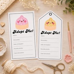 Op de afbeelding: Twee rechthoekige witte papieren labels met zwarte randen en de tekst Adopt Me! gevolgd door lijnen voor Naam, Persoonlijkheid, Adoptiedatum, Favoriete activiteit en Verzorgingsinstructies. Eén label toont een roze glitterende knoedel, de andere een gouden.