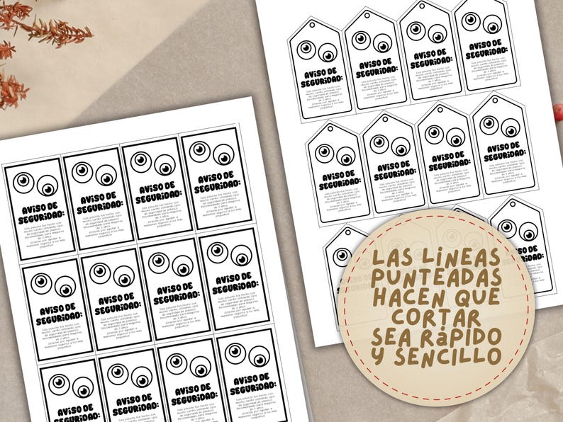 May include: Printed sheets of paper with black and white safety warning tags and rectangular cards. Each tag and card features cartoon eyes and the text "AVISO DE SEGURIDAD". A circular label reads "LAS LINEAS PUNTEADAS HACEN QUE CORTAR SEA R&Aacute;PIDO Y SENCILLO".
