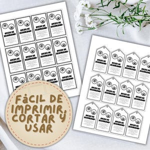 May include: Two sheets of printed paper with black text and eye graphics. One sheet has rectangular labels, the other has tag-shaped labels. The text on the labels reads "AVISO DE SEGURIDAD". A circular label says "F&Aacute;CIL DE IMPRIMIR, CORTAR Y USAR".