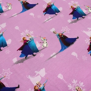 Pode incluir: Tecido rosa com um padrão repetido de duas meninas do filme Frozen, Elsa e Anna, patinando com Olaf, o boneco de neve. O fundo é rosa claro com flocos de neve brancos e desenhos florais.