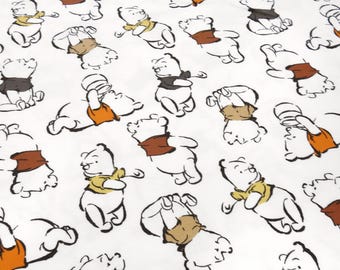 Puede incluir: Tela blanca con un patrón repetido de Winnie de Pooh en varias poses. La tela presenta un fondo blanco con contornos negros y acentos marrones, naranjas y amarillos.