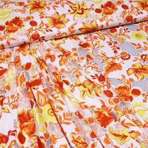 Könnte beinhalten: Weißer, durchsichtiger Stoff mit einem floralen Muster in Orange- und Gelbtönen. Die Blumen sind stilisiert und haben einen Vintage-Look.