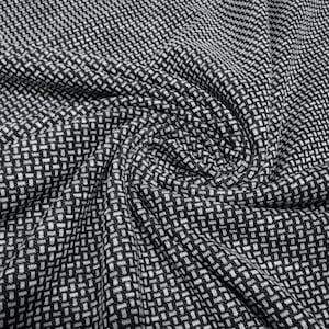 Puede incluir: Primer plano de una tela tejida en blanco y negro con un patrón de tejido de cesta. La tela está tejida apretadamente, creando una superficie texturizada. El patrón es una cuadrícula repetitiva de cuadrados blancos y negros, creando una textura visual.