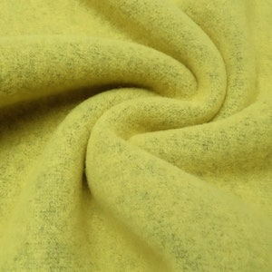 May include: A close-up of a soft, yellow fabric with a fuzzy texture. The fabric is folded and draped, showing its texture and colour.