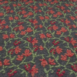 Peut inclure: Gros plan sur un tissu gris avec un motif floral répétitif. Le motif présente des fleurs et des baies rouges avec des vignes vertes. La texture du tissu semble douce et légèrement en relief, créant un effet tridimensionnel.