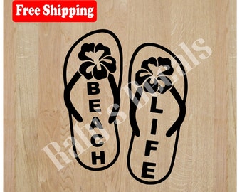 Op de afbeelding: Zwarte en witte silhouet van twee slippers met de woorden "Beach Life" erop. De slippers hebben een bloemenmotief op de band.