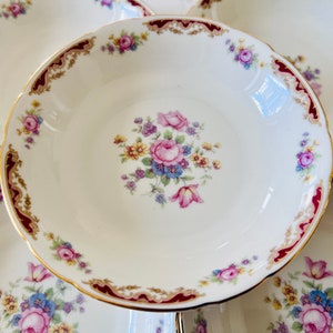 May include: Set of six white ceramic bowls with a gold and burgundy rim and floral design. The bowls have a scalloped edge and are perfect for serving soup, salad, or dessert.