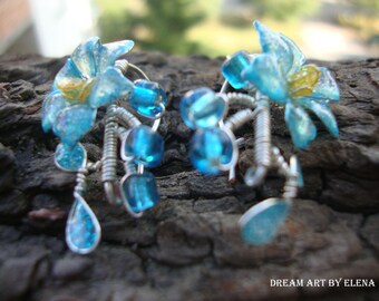 Miniature flower earrings in sparkling translucent blue, darker on the edges, with yellow stamens, stylized leaves and beads
