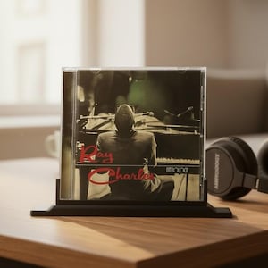 May include: A Ray Charles Anthology music CD in a clear plastic jewel case. The cover art features a black and white photograph of a person sitting at a piano, with the name Ray Charles printed in red script and the word Anthology in white text.