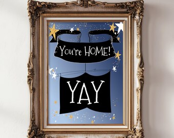 Puede incluir: Una impresión artística enmarcada con un fondo degradado azul con estrellas doradas y blancas. Una pancarta negra en la parte superior muestra el texto "YOU'RE HOME!" y una segunda pancarta negra debajo muestra el texto "YAY" en letras blancas.
