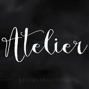 Op de afbeelding: Het woord Atelier is geschreven in een wit, cursief handschrift-lettertype, gecentreerd tegen een donkere, getextureerde zwarte achtergrond. De tekst bevat elegante lussen en krullen, wat zorgt voor een contrastrijke weergave van het woord.