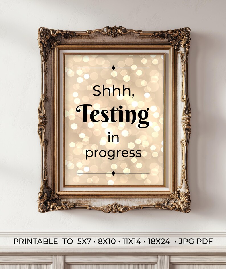 Pu&ograve; includere: Un cartello da parete rettangolare in una cornice ornata color oro antico. La stampa presenta uno sfondo beige con un effetto di luce bokeh bianca sfocata. Il testo recita: Shhh, Testing in progress, con linee orizzontali sopra e sotto.