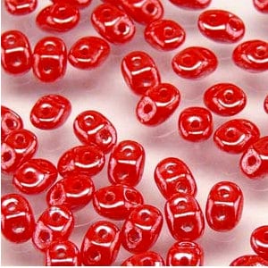 May include: A large quantity of small, red, oval-shaped glass beads with a hole through the center. The beads have a glossy finish.