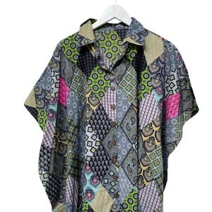 Pu&ograve; includere: Una camicia a maniche corte con un design patchwork. La camicia presenta una variet&agrave; di motivi nelle tonalit&agrave; di grigio, nero, verde, rosa e giallo. &Egrave; abbottonata e appesa a una gruccia bianca.