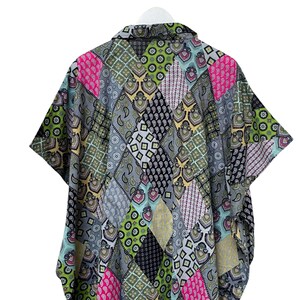 Pu&ograve; includere: Una camicia a maniche corte con un design patchwork. La camicia presenta una variet&agrave; di motivi nelle tonalit&agrave; di grigio, rosa, verde e nero. La camicia &egrave; appesa a una gruccia bianca.
