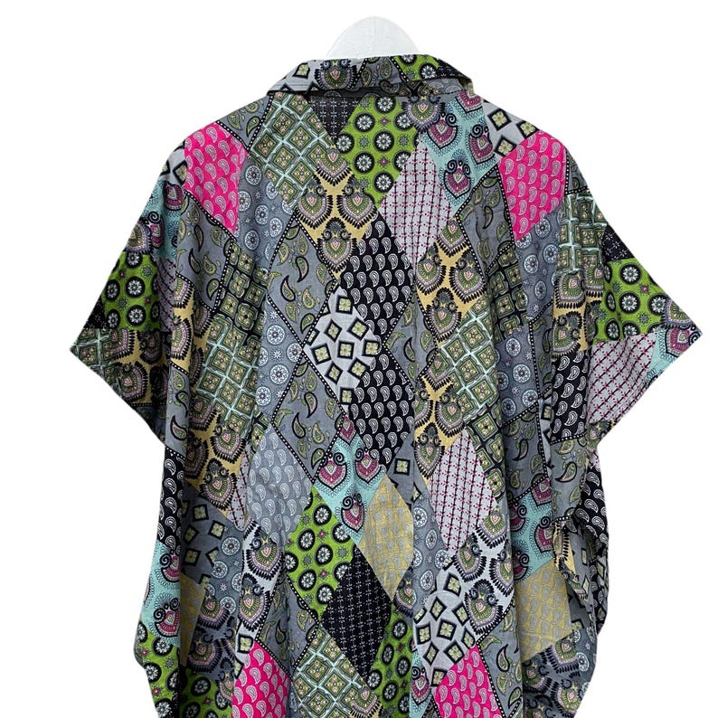 Pu&ograve; includere: Una camicia a maniche corte con un design patchwork. La camicia presenta una variet&agrave; di motivi nelle tonalit&agrave; di grigio, rosa, verde e nero. La camicia &egrave; appesa a una gruccia bianca.