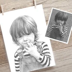 May include: A black and white pencil drawing of a young child with short, choppy hair wearing a striped shirt and overalls. The child is biting their finger.