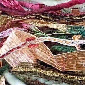 May include: A collection of assorted decorative ribbons and trims in various textures and colors, including metallic gold, deep green, magenta, and copper. The assortment features intricate woven patterns, frayed edges, and delicate embroidery.
