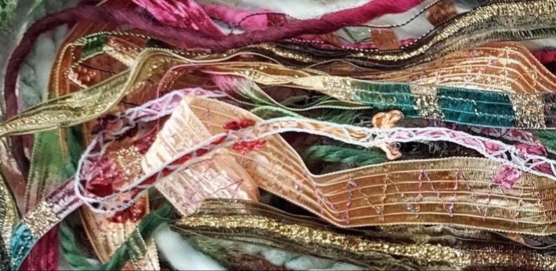 May include: A collection of assorted decorative ribbons and trims in various textures and colors, including metallic gold, deep green, magenta, and copper. The assortment features intricate woven patterns, frayed edges, and delicate embroidery.
