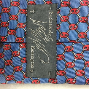 May include: A black tie with a white label that reads "Exclusive!  Navy & Kensington". The tie has a blue background with a repeating pattern of red circles connected by white rope.