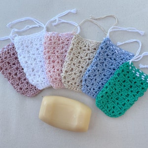 May include: Six crocheted soap pouches in various colors, including pink, white, beige, blue, and green, with a bar of soap in the center.