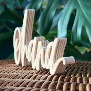May include: A handmade wooden sign with the text "Welcome" in a playful font. The sign is painted white with a distressed finish, and features a small, decorative heart. Dimensions are approximately 12 inches wide and 6 inches tall.