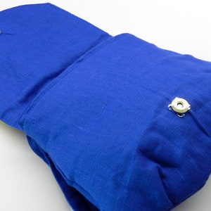 May include: A vibrant blue fabric bag with a flap closure and a magnetic snap. The bag has a rectangular shape with rounded edges and a strap. The interior is a lighter color, and the bag appears to be made of linen or a similar material.