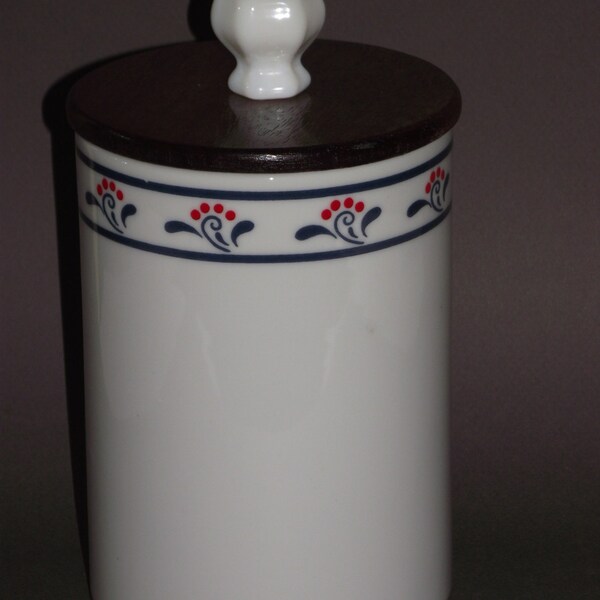 White ceramic container Made in Japan, vividly colored  with a baked on red and blue motif , black walnut lid  and a white glass knob.