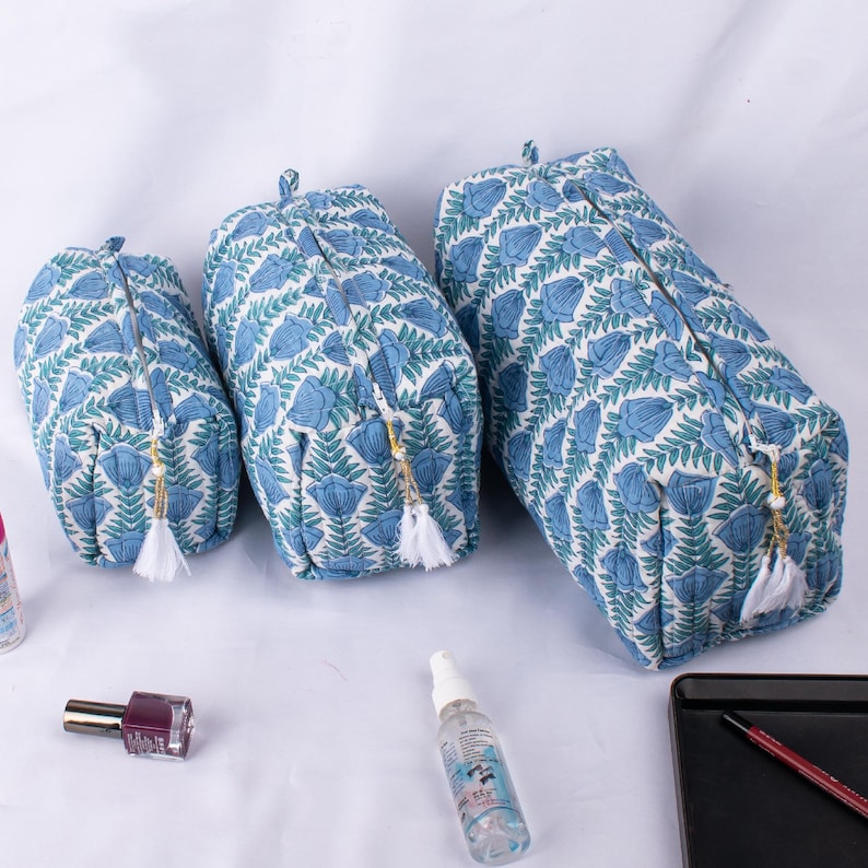 May include: Three blue and white floral print zippered pouches of different sizes. The pouches have a white tassel zipper pull.