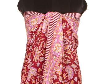 May include: A sarong featuring a deep red base color with a floral pattern in shades of pink, orange, and white. The fabric includes a vertical border with a white and red striped design that runs down the center and along the top edge.