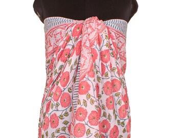 May include: A sarong featuring a light pink background with a repeating pattern of vibrant coral-colored flowers and green leaves. The fabric displays a decorative border with thin blue and white stripes, draped over a black mannequin torso.