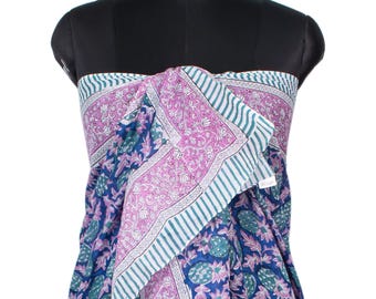 May include: A sarong featuring a vibrant pattern of blue and green pineapples set against a deep blue background, accented by a wide border of pink floral motifs and white and teal stripes, draped over a black mannequin torso for display.