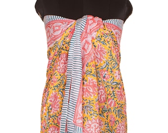 May include: A sarong featuring a vibrant yellow background with a repeating floral pattern in shades of pink and green. The fabric includes a vertical border with thin white and dark teal stripes, creating a distinct contrast against the floral print.