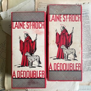May include: Two vintage red and white cardboard boxes with the text "LAINE ST-ROCH A DÉDOUBLER" printed on them. Each box features an illustration of a saint in red robes with a dog.