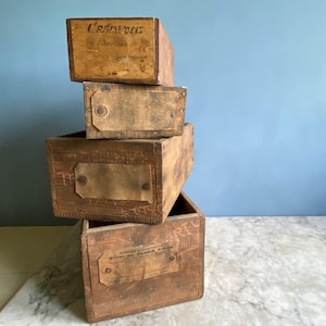 Può includere: Quattro scatole di legno vintage impilate l'una sull'altra. La scatola superiore ha un'etichetta che recita "L'RIALTOIS" e la scatola inferiore ha un'etichetta che recita "MANUFACTURED BY G.C. SMITH & CO. PARIS".