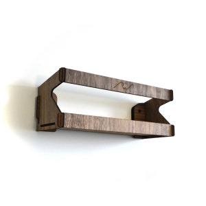 May include: A wooden wall shelf with two tiers. The shelf is made of dark wood with a natural grain pattern. The shelf is mounted on a white wall.
