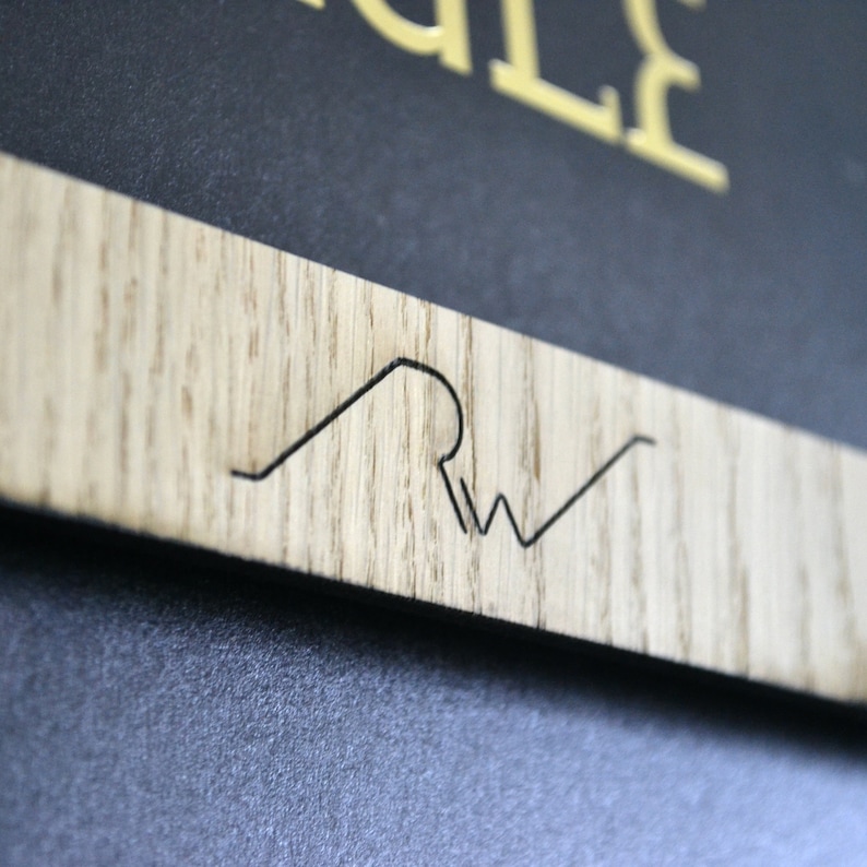 May include: A close-up of a wooden sign with a black engraved logo. The logo is a stylized wave with the letters "RW" inside.