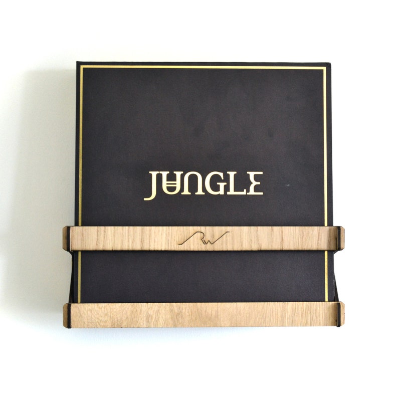May include: A black vinyl record with a gold border and the word "JUNGLE" printed in gold letters. The record is displayed on a wooden wall mount with a small logo.