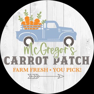 May include: Round wooden sign with a light blue truck carrying orange carrots. The sign reads "McGregor's Carrot Patch" with the text "Farm Fresh • You Pick!" and an arrow graphic. The background has a white wood grain pattern.