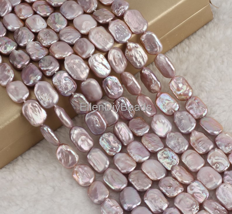 May include: A strand of lavender-colored freshwater pearl beads. The beads are oval-shaped and have a slightly irregular shape. The pearls have a subtle iridescent sheen.