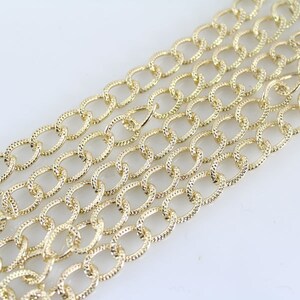 May include: A gold chain with a textured oval link design. The chain is made of metal and is suitable for jewelry making or crafting projects.