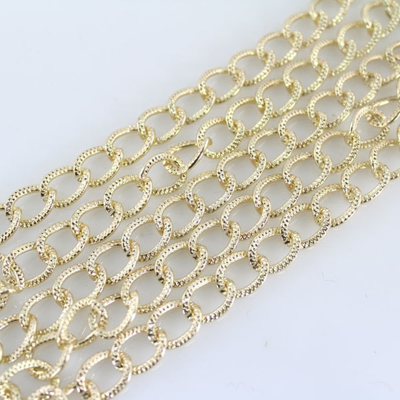 May include: A gold chain with a textured oval link design. The chain is made of metal and is suitable for jewelry making or crafting projects.