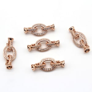 May include: Five gold-tone metal connector clasps with clear crystal embellishments. Each clasp has a round, oval-shaped design.